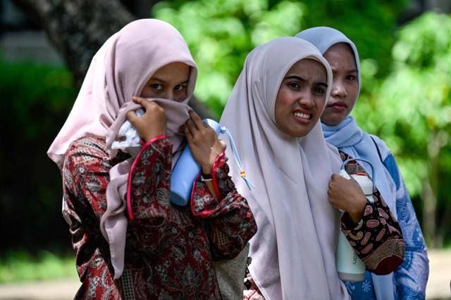 Women watch as a couple who allegedly had sexual intercourse on a TikTok livestream receive a caning as punishment under sharia law in Banda Aceh on July 2, 2026. (Photo by CHAIDEER MAHYUDDIN / AFP)
