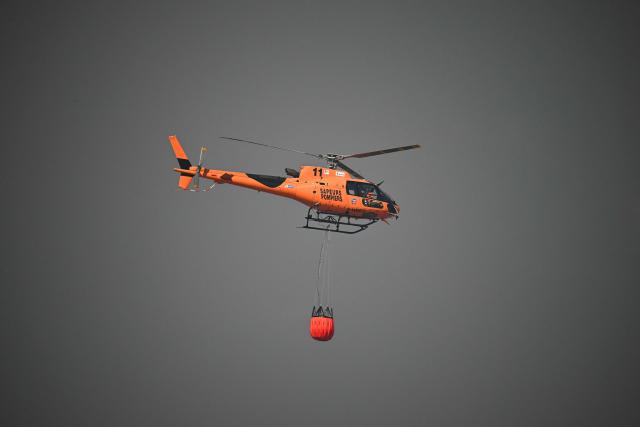A firefighter F-HBEO water bomber helicopter flies during a wildfire in Pouzols-Minervois, southern France on July 2, 2026. One year after the wildfire in the Corbières massif, the south of France has once again been hit by a large-scale blaze that broke out on July 1, 2026 afternoon in the Herault before quickly spreading to the neighboring department of Aude under the combined effect of drought and wind, and is being fought by hundreds of firefighters. (Photo by Lionel BONAVENTURE / AFP)