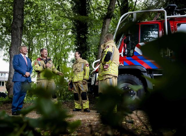 King Willem-Alexander of The Netherlands speaks with firefighters during a visit in Austerlitz, near Utrecht, focused on wildfires preventive measures taken at local, regional, and national levels, on July 2, 2026. (Photo by Sem van der Wal / ANP / AFP) / Netherlands OUT