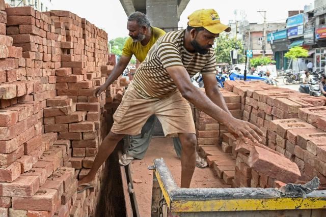 Workers load bricks onto a tractor trolley along a road in Amritsar on July 2, 2026. (Photo by Narinder NANU / AFP)