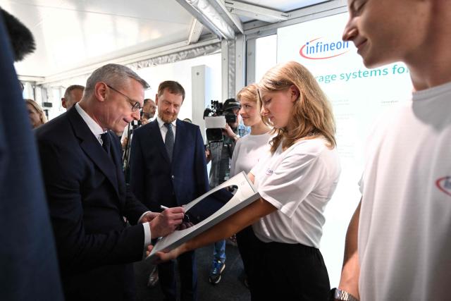 German Minister for Digitalization and State Modernization Karsten Wildberger (L) and Saxony's State Premier Michael Kretschmer(C Back) greet apprentices at the opening of the Infineon Smart Power Fab in Dresden, eastern Germany, on July 2, 2026. German semiconductor giant Infineon officially opens a large new chip factory in eastern Germany on July 2, three months ahead of schedule. The new, highly automated plant -- which cost 5 billion euros ($5.7 billion) -- has been repeatedly held up as a symbol of the European Union's push to bolster the domestic tech sector and reduce dependency for crucial parts on Asia and the United States. (Photo by Robert Michael / POOL / AFP)