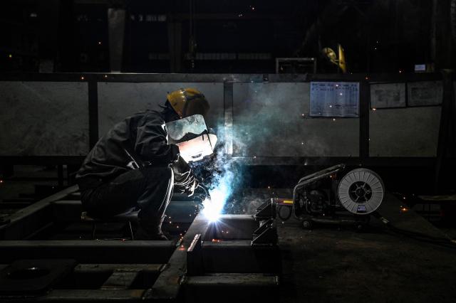 The photo taken on March 11, 2026 shows a worker manufacturing parts for automotive equipment at Miracle Automation Engineering Company in Wuxi, in eastern China's Jiangsu province. (Photo by Jade GAO / AFP)