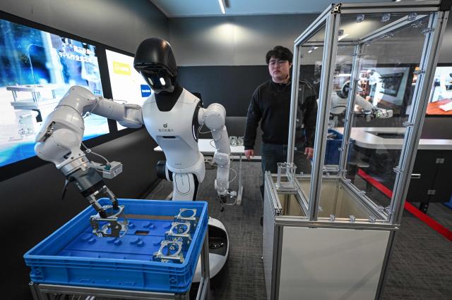 The photo taken on March 11, 2026 shows a robot lifting steel products at Agibot's headquarter in Shanghai. (Photo by Jade GAO / AFP)