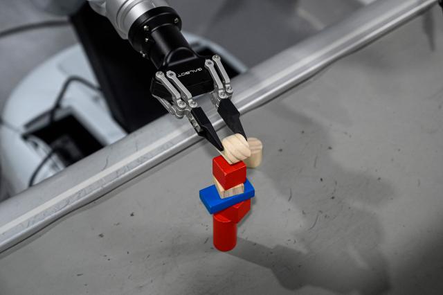 The photo taken on March 11, 2026 shows a robot placing a block at a robot data training center of Miracle Automation Engineering Company in Wuxi, in eastern China's Jiangsu province. (Photo by Jade GAO / AFP)