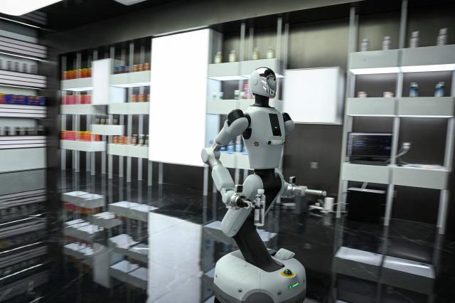 The photo taken on March 11, 2026 shows a robot grabbing a bottle of water at a robot data training center of Miracle Automation Engineering Company in Wuxi, in eastern China's Jiangsu province. (Photo by Jade GAO / AFP)