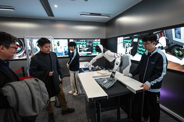 The photo taken on March 11, 2026 shows a robot placing packages onto a delivery belt at Agibot's headquarter in Shanghai. (Photo by Jade GAO / AFP)
