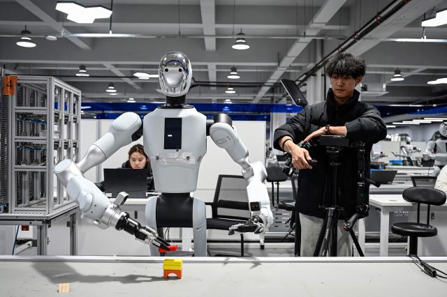 The photo taken on March 11, 2026 shows technicians conducting robot training at a robot data training center of Miracle Automation Engineering Company in Wuxi, in eastern China's Jiangsu province. (Photo by Jade GAO / AFP)