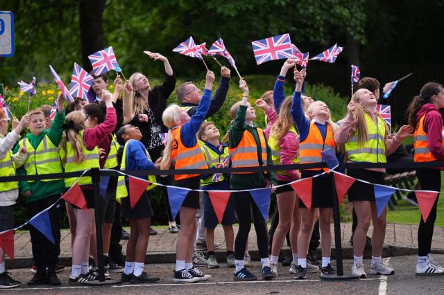Children wave at the helicopter Britain's King Charles III is arriving in for his visit which coincides with the Jethart Callant Festival in Jedburgh, Scotland on July 2, 2026. (Photo by Aaron Chown / POOL / AFP)
