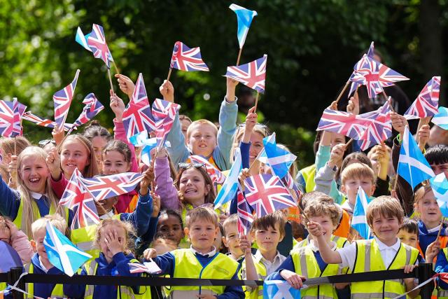 Children wave flags as Britain's King Charles III (not pictured) visits to coincide with the Jethart Callant Festival in Jedburgh, Scotland on July 2, 2026. (Photo by Aaron Chown / POOL / AFP)