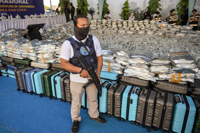 A National Narcotics Agency officer stands next to packages of seized cannabis buds during a press conference in Gresik, East Java Province, on July 2, 2026. The National Narcotics Agency (BNN) in collaboration with Customs and the police foiled an attempt to smuggle 3.37 metric tons of cannabis buds from Thailand and apprehended 12 suspected perpetrators. (Photo by Juni KRISWANTO / AFP)