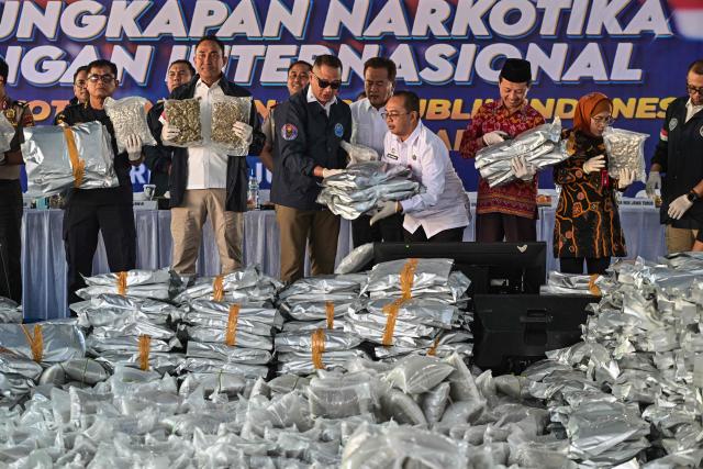 Customs officers and the National Narcotics Agency show packages of seized cannabis buds during a press conference in Gresik, East Java Province, on July 2, 2026. The National Narcotics Agency (BNN) in collaboration with Customs and the police foiled an attempt to smuggle 3.37 metric tons of cannabis buds from Thailand and apprehended 12 suspected perpetrators. (Photo by Juni KRISWANTO / AFP)