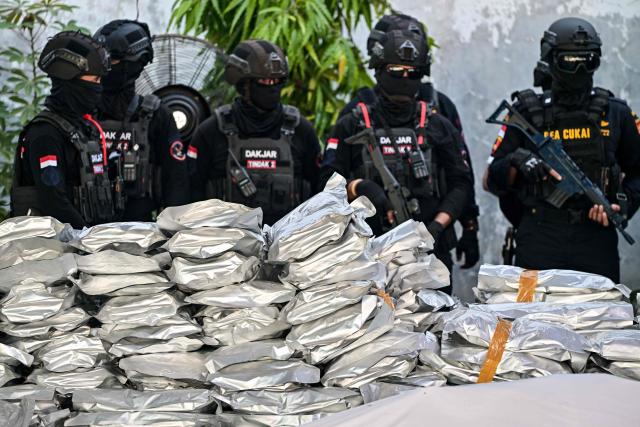 Customs officers stands next to packages of seized cannabis buds during a press conference in Gresik, East Java Province, on July 2, 2026. The National Narcotics Agency (BNN) in collaboration with Customs and the police foiled an attempt to smuggle 3.37 metric tons of cannabis buds from Thailand and apprehended 12 suspected perpetrators. (Photo by Juni KRISWANTO / AFP)