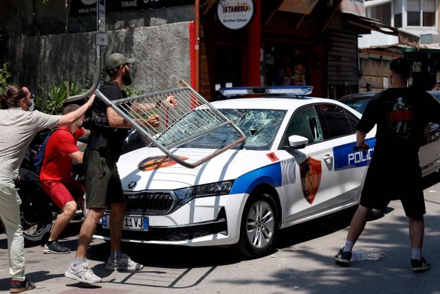 Protesters destroy the windshield of a police car with a barricade as violent clashes erupted between police and demonstrators on the sidelines of a demonstration against a controversial luxury resort development linked to US President near a protected natural area, outside the parliament, in Tirana, on July 2, 2026. Since late May, protests have been held against the construction of a luxury hotel linked to Donald Trump's daughter and her husband in a nature reserve in Zvernec, on Albania's southwestern coast. For the second time this week, large groups of protesters had gathered outside the country's parliament in an attempt to confront lawmakers and block entry to the building. (Photo by Adnan Beci / AFP)