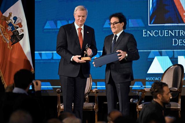 Chile's President Jose Antonio Kast (L) receives a statuette representing democracy from the president of the Association of Marketing Executives of Uruguay (ADM), Jorge Abuchalja, during a breakfast organized by the ADM in Montevideo on July 2, 2026. Kast is on official visit in Uruguay. (Photo by Santiago Mazzarovich / AFP)