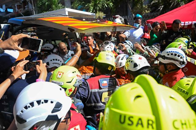 An international rescue team assists Hernan Gil, a survivor of Venezuela's twin earthquakes, in Catia La Mar, La Guaira State, Venezuela on July 2, 2026, eight days after the quake. Hernan Gil, a 43-year-old security guard, had been buried in the booth of the seven-story building where he worked in Catia La Mar, a coastal area in the state of La Guaira devastated by the disaster. (Photo by Federico PARRA / AFP)