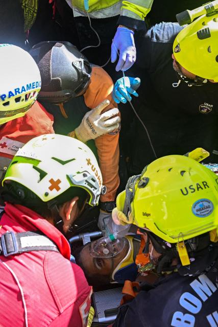 Members of international rescue teams assist Hernan Gil, a survivor of Venezuela's twin earthquakes, before rushing him into an ambulance in Catia La Mar, La Guaira State, Venezuela on July 2, 2026, eight days after the quake. Hernan Gil, a 43-year-old security guard, had been buried in the booth of the seven-story building where he worked in Catia La Mar, a coastal area in the state of La Guaira devastated by the disaster. (Photo by Federico PARRA / AFP)