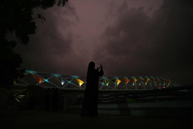 A woman takes a picture at Sabarmati riverfront in Ahmedabad on July 2, 2026. (Photo by Shammi MEHRA / AFP)