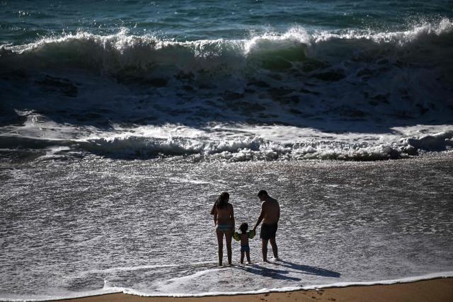 A couple and a child stand on the beach facing strong waves in Labenne, southwestern France on July 1, 2026. (Photo by Christophe ARCHAMBAULT / AFP)
