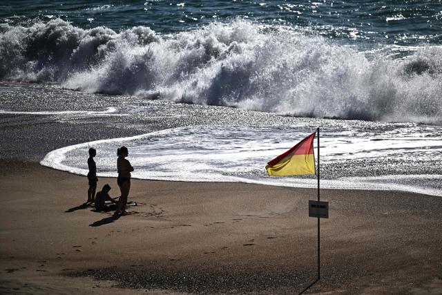 Bathers enjoy the beach as strong waves hit the shore in Labenne, southwestern France on July 1, 2026. (Photo by Christophe ARCHAMBAULT / AFP)