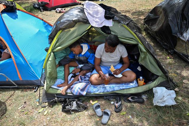 A woman eats next to a child at a displaced camp at the Ali West Park in Caracas on July 2, 2026, eight days after twin earthquakes. Hundreds of rescuers in Venezuela cheered and embraced on July 2, 2026 after pulling 43-year-old Hernan Gil from the ruins of a collapsed building eight days after deadly twin earthquakes, AFP journalists witnessed. (Photo by MARTIN BERNETTI / AFP)