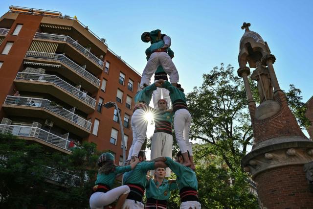 Performers form a Castell, a traditional Catalan human tower, on the sidelines of the team presentation ceremony ahead of the 113th edition of the Tour de France cycling race, with the Sagrada Familia Basilica seen in the background, in Barcelona, northeastern Spain, on July 2, 2026. (Photo by Jeff PACHOUD / AFP)