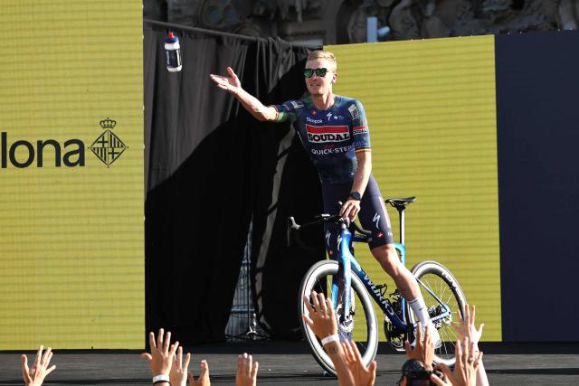 CORRECTION / Soudal Quick-Step team's Belgian rider Tim Merlier attends the team presentation ceremony ahead of the 113th edition of the Tour de France cycling race, with the Sagrada Familia Basilica  seen in the background, in Barcelona, northeastern Spain, on July 2, 2026. (Photo by Anne-Christine POUJOULAT / AFP) / The erroneous mention[s] appearing in the metadata of this photo by Anne-Christine POUJOULAT has been modified in AFP systems in the following manner: [Soudal Quick-Step team's Belgian rider Tim Merlier] instead of [Soudal Quick-Step team's French rider Valentin Paret-Peintre]. Please immediately remove the erroneous mention[s] from all your online services and delete it (them) from your servers. If you have been authorized by AFP to distribute it (them) to third parties, please ensure that the same actions are carried out by them. Failure to promptly comply with these instructions will entail liability on your part for any continued or post notification usage. Therefore we thank you very much for all your attention and prompt action. We are sorry for the inconvenience this notification may cause and remain at your disposal for any further information you may require.