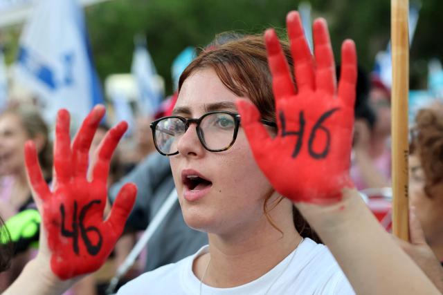 An Israeli woman displays her hands painted red during rally against the government and the war in Gaza, at Hostage Square in Tel Aviv, on July 2, 2026, marking 1000 days since Hamas's October 7, 2023 attack on Israel. Israelis called on July 2 for a state commission of inquiry into Hamas's October 7, 2023 attack, as the country marked 1,000 days since the deadliest event in its history, which triggered the war in Gaza. A series of sombre commemorations were being held across the country, as well as protests against the government's handling of events during and after the attack. (Photo by Jack GUEZ / AFP)