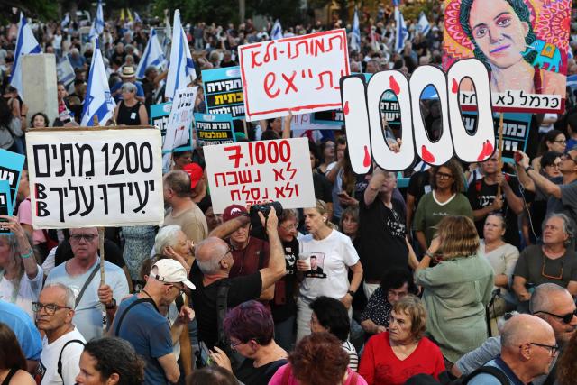 Israeli protesters hold placards during a rally against the government and the war in Gaza, at Hostage Square in Tel Aviv, on July 2, 2026, marking 1000 days since Hamas's October 7, 2023 attack on Israel. Israelis called on July 2 for a state commission of inquiry into Hamas's October 7, 2023 attack, as the country marked 1,000 days since the deadliest event in its history, which triggered the war in Gaza. A series of sombre commemorations were being held across the country, as well as protests against the government's handling of events during and after the attack. (Photo by Jack GUEZ / AFP)