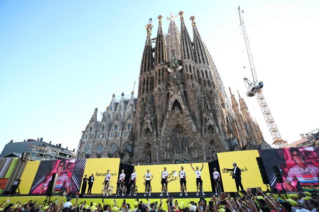 TOPSHOT - UAE Team Emirates - XRG riders attend the team presentation ceremony ahead of the 113th edition of the Tour de France cycling race, with the Sagrada Familia Basilica  seen in the background, in Barcelona, northeastern Spain, on July 2, 2026. (Photo by Anne-Christine POUJOULAT / AFP)