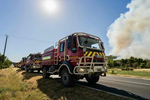 This photograph shows a firefighting vehicle parked on a road as a wildfire rages in Pouzols-Minervois, southwestern of France,  on July 2, 2026. Hundreds of firefighters are battling wildfires in the south that are being fueled by wind, drought, and heat. The largest fire is in the Aude department, but there are also fires north of Marseille, where Prime Minister is expected to chair a new interministerial crisis task force. (Photo by Idriss Bigou-Gilles / AFP)