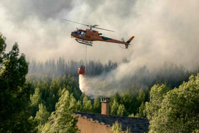 This photograph shows a firefighter water bomber helicopter flying over a wildfire raging in Pouzols-Minervois, southwestern of France,  on July 2, 2026. Hundreds of firefighters are battling wildfires in the south that are being fueled by wind, drought, and heat. The largest fire is in the Aude department, but there are also fires north of Marseille, where Prime Minister is expected to chair a new interministerial crisis task force. (Photo by Idriss Bigou-Gilles / AFP)