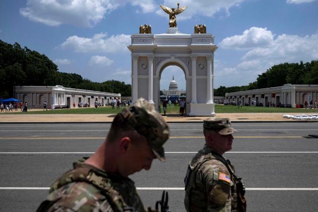 National Guard Members walk along the street in view of a replica of President Trump’s planned “Triumphal Arch” as people visit the Great American State Fair on the National Mall in Washington, DC, on July 2, 2026, ahead of the upcoming July 4 holiday. (Photo by Kent Nishimura / AFP)