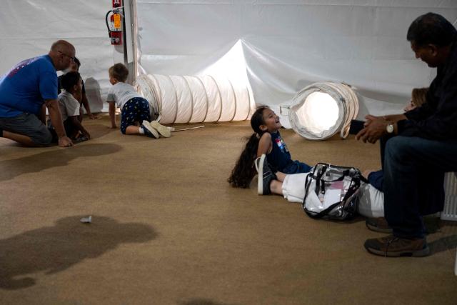 People sit in front of vents pumping cool air into a tent as they visit the "Great American State Fair" on the National Mall in Washington, DC, on July 2, 2026, ahead of the upcoming July 4 holiday. Americans sweltered under furnace-like temperatures this week as central and eastern cities hunkered down for a heat wave set to last through the July 4 holiday weekend. Dozens of local temperature records could be broken, the National Weather Service (NWS) warned, with temperatures in many places to surpass 100 degrees Fahrenheit (38 degrees Celsius) and high humidity pushing the heat index as high as 115 degrees. (Photo by Kent Nishimura / AFP)