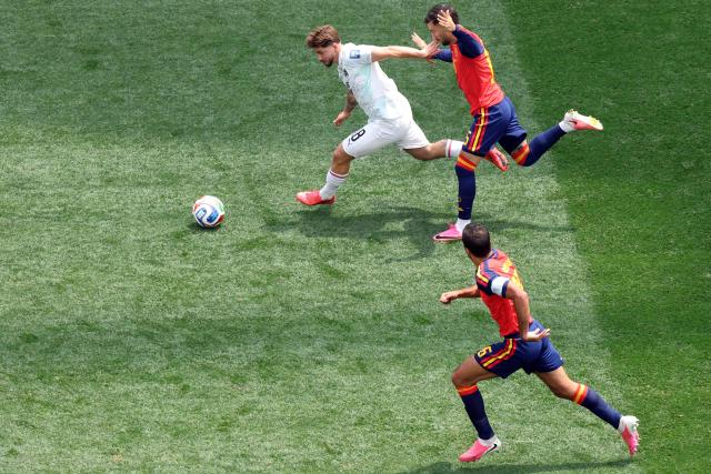 Austria's midfielder #18 Romano Schmid (L) runs with the ball past Spain's midfielder #15 Alex Baena (R) and midfielder #16 Rodri (bottom) during the 2026 World Cup round of 32 football match between Spain and Austria at the Los Angeles Stadium in Inglewood on July 2, 2026.  (Photo by VALERIE MACON / AFP)