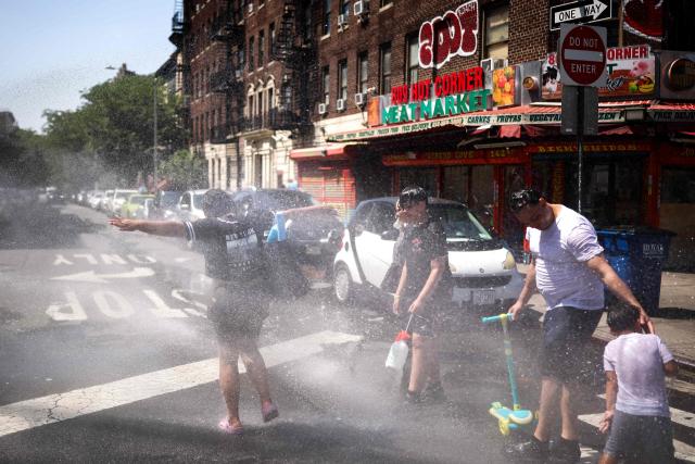 A family cools off at a fire hydrant in the Hamilton Heights neighborhood in the Manhattan borough of New York City on July 2, 2026. Blistering temperatures and humidity gripped swaths of the United States on July 1, with the worst yet to come for the densely populated East Coast as the nation co-hosts the World Cup and prepares to celebrate its 250th birthday. "Heat dome" conditions -- in which high-pressure systems trap warm air like the lid on a pot -- persisted over the Midwest and South and were moving east, with some 46 million people under heat alerts. (Photo by CHARLY TRIBALLEAU / AFP)