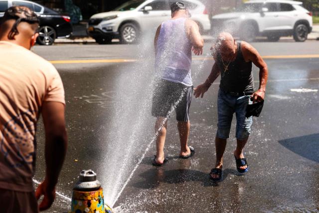 Men cool off at a fire hydrant in the Hamilton Heights neighborhood in the Manhattan borough of New York City on July 2, 2026. Blistering temperatures and humidity gripped swaths of the United States on July 1, with the worst yet to come for the densely populated East Coast as the nation co-hosts the World Cup and prepares to celebrate its 250th birthday. "Heat dome" conditions -- in which high-pressure systems trap warm air like the lid on a pot -- persisted over the Midwest and South and were moving east, with some 46 million people under heat alerts. (Photo by CHARLY TRIBALLEAU / AFP)