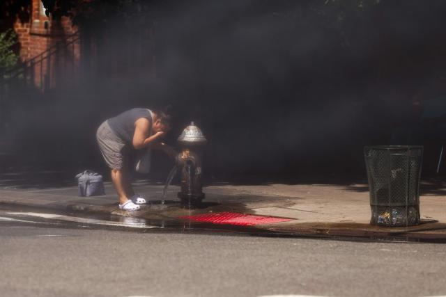 A woman cools off at a fire hydrant in the Hamilton Heights neighborhood in the Manhattan borough of New York City on July 2, 2026. Blistering temperatures and humidity gripped swaths of the United States on July 1, with the worst yet to come for the densely populated East Coast as the nation co-hosts the World Cup and prepares to celebrate its 250th birthday. "Heat dome" conditions -- in which high-pressure systems trap warm air like the lid on a pot -- persisted over the Midwest and South and were moving east, with some 46 million people under heat alerts. (Photo by CHARLY TRIBALLEAU / AFP)