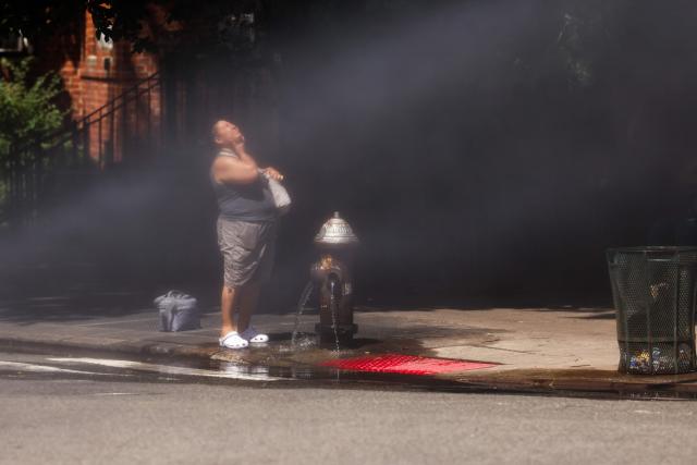 A woman cools off at a fire hydrant in the Hamilton Heights neighborhood in the Manhattan borough of New York City on July 2, 2026. Blistering temperatures and humidity gripped swaths of the United States on July 1, with the worst yet to come for the densely populated East Coast as the nation co-hosts the World Cup and prepares to celebrate its 250th birthday. "Heat dome" conditions -- in which high-pressure systems trap warm air like the lid on a pot -- persisted over the Midwest and South and were moving east, with some 46 million people under heat alerts. (Photo by CHARLY TRIBALLEAU / AFP)