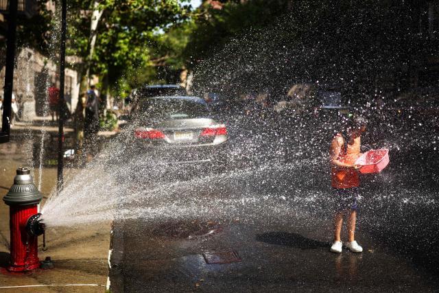 A child cools off at a fire hydrant in the Hamilton Heights area in the Manhattan borough of New York City on July 2, 2026. Blistering temperatures and humidity gripped swaths of the United States on July 1, with the worst yet to come for the densely populated East Coast as the nation co-hosts the World Cup and prepares to celebrate its 250th birthday. "Heat dome" conditions -- in which high-pressure systems trap warm air like the lid on a pot -- persisted over the Midwest and South and were moving east, with some 46 million people under heat alerts. (Photo by CHARLY TRIBALLEAU / AFP)