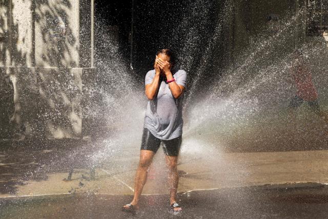 A woman cools off at a fire hydrant in the Hamilton Heights area in the Manhattan borough of New York City on July 2, 2026. Blistering temperatures and humidity gripped swaths of the United States on July 1, with the worst yet to come for the densely populated East Coast as the nation co-hosts the World Cup and prepares to celebrate its 250th birthday. "Heat dome" conditions -- in which high-pressure systems trap warm air like the lid on a pot -- persisted over the Midwest and South and were moving east, with some 46 million people under heat alerts. (Photo by CHARLY TRIBALLEAU / AFP)