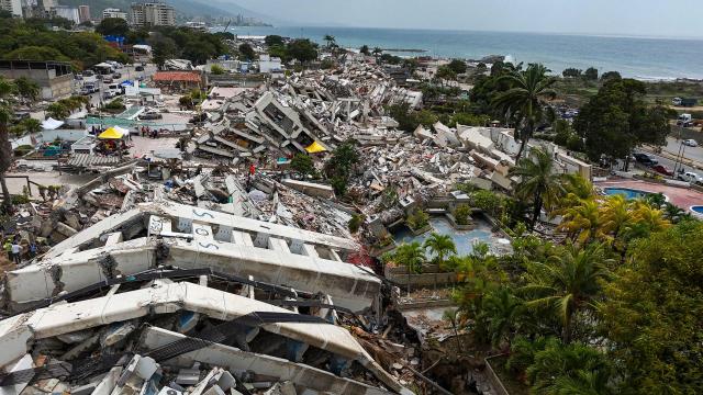 This aerial photograph taken on July 2, 2026 in Caraballeda in the state of La Guaira shows collapsed buildings following the June 24 twin earthquakes. More than a week after the earthquakes struck, there is little chance of finding additional survivors from the two earthquakes that killed nearly 2,300 people, destroyed entire residential buildings, and left tens of thousands missing. (Photo by Miguel MEDINA / POOL / AFP)