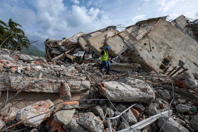 This photograph taken on July 2, 2026 in Caraballeda in the state of La Guaira shows a volunteer walking amid rubble in a collapsed building following the June 24 twin earthquakes. More than a week after the earthquakes struck, there is little chance of finding additional survivors from the two earthquakes that killed nearly 2,300 people, destroyed entire residential buildings, and left tens of thousands missing. (Photo by Miguel MEDINA / POOL / AFP)