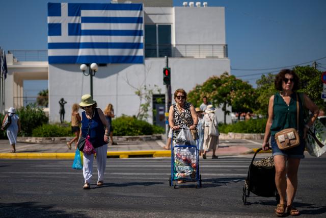 Residents of the southern Athenian suburb of Glyfada cross a highway after shoping from a public market on July 2, 2026. Less than 15 km from the center of Athens, Glyfada—like many neighborhoods along the Saronic Gulf—has seen its population grow in recent years due to a major real estate development underway in the neighboring municipality of Ellinikon, leading to skyrocketing prices.
Nicknamed “The Athenian Riviera”, this massive development project, spanning an area of 6.2 kmІ, will soon include hotels, shopping centers, parks, marinas, 8,000 housing units, and a “new city” of 30,000 residents, according to Lamda Development, the company in charge. (Photo by Aris MESSINIS / AFP)