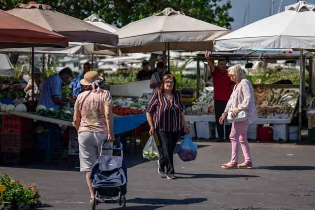 Residents of the southern Athenian suburb of Glyfada cross a highway after shoping from a public market on July 2, 2026. Less than 15 km from the center of Athens, Glyfada—like many neighborhoods along the Saronic Gulf—has seen its population grow in recent years due to a major real estate development underway in the neighboring municipality of Ellinikon, leading to skyrocketing prices.
Nicknamed “The Athenian Riviera”, this massive development project, spanning an area of 6.2 kmІ, will soon include hotels, shopping centers, parks, marinas, 8,000 housing units, and a “new city” of 30,000 residents, according to Lamda Development, the company in charge. (Photo by Aris MESSINIS / AFP)