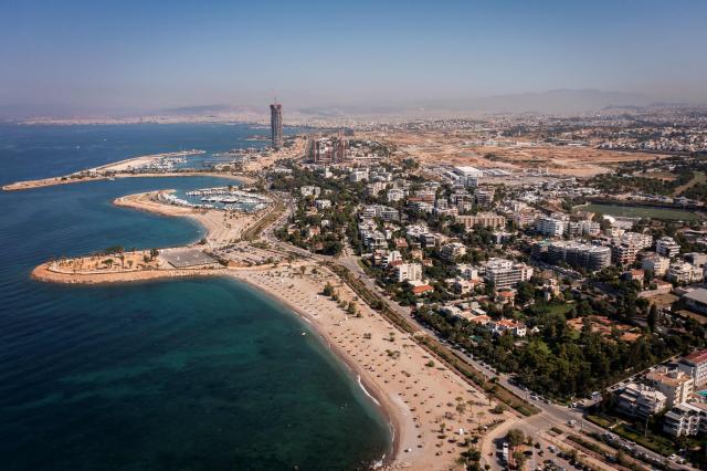 An aerial view shows the southern Athenian suburb of Glyfada on July 2, 2026. Less than 15 km from the center of Athens, Glyfada—like many neighborhoods along the Saronic Gulf—has seen its population grow in recent years due to a major real estate development underway in the neighboring municipality of Ellinikon, leading to skyrocketing prices.
Nicknamed “The Athenian Riviera”, this massive development project, spanning an area of 6.2 kmІ, will soon include hotels, shopping centers, parks, marinas, 8,000 housing units, and a “new city” of 30,000 residents, according to Lamda Development, the company in charge. (Photo by Aris MESSINIS / AFP)