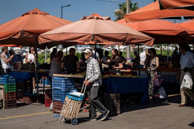 Residents of the southern Athenian suburb of Glyfada cross a highway after shoping from a public market on July 2, 2026. Less than 15 km from the center of Athens, Glyfada—like many neighborhoods along the Saronic Gulf—has seen its population grow in recent years due to a major real estate development underway in the neighboring municipality of Ellinikon, leading to skyrocketing prices.
Nicknamed “The Athenian Riviera”, this massive development project, spanning an area of 6.2 kmІ, will soon include hotels, shopping centers, parks, marinas, 8,000 housing units, and a “new city” of 30,000 residents, according to Lamda Development, the company in charge. (Photo by Aris MESSINIS / AFP)