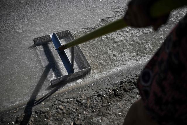 French salt maker Annabelle Poinot harvests salt flower forming a thin crust on the surface of seawater drained through the basins of a salt marsh in Chateau-d'Olйron, on the Oleron Island, western France on June 17, 2026. The profession of salt worker, which disappeared from Olйron Island in the 1980s, was reintroduced with the support of local authorities because salt marshes, as “buffer” zones, can absorb part of the marine flooding, which is becoming increasingly frequent with climate change. (Photo by Christophe ARCHAMBAULT / AFP)