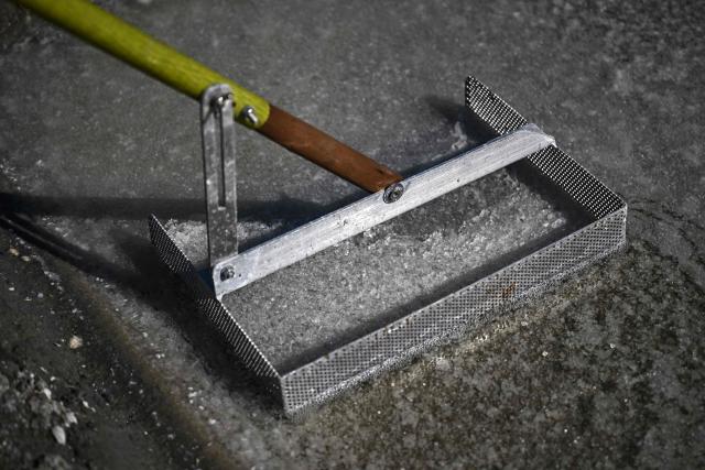 This photograph shows a 'simoussi' a tool used to harvest salt flower formed as a thin crust on the surface of seawater drained through the basins of a salt marsh in Chateau-d'Olйron, on the Oleron Island, south-western France on June 17, 2026. The profession of salt worker, which disappeared from Olйron Island in the 1980s, was reintroduced with the support of local authorities because salt marshes, as “buffer” zones, can absorb part of the marine flooding, which is becoming increasingly frequent with climate change. (Photo by Christophe ARCHAMBAULT / AFP)