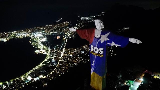 This aerial view shows the Christ the Redeemer monument illuminated in the colors of the Venezuelan flag and displaying the message "SOS Venezuela" in solidarity with the victims of the deadly twin earthquakes that struck on June 24, in Rio de Janeiro, Brazil, on July 2, 2026. (Photo by Jose Osorio / AFP)