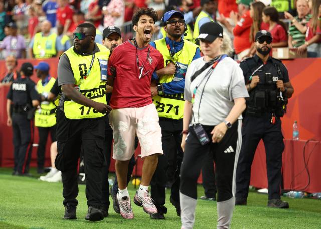 Security guards detain a pitch invader during the 2026 World Cup round of 32 football match between Portugal and Croatia at the Toronto Stadium in Toronto on July 2, 2026.  (Photo by Cole Burston / AFP)